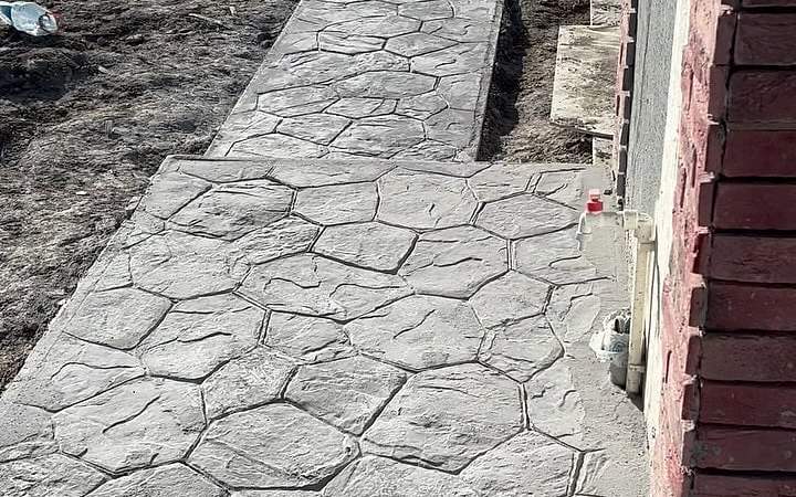 Bina kenarında taş desenli baskı beton yürüyüş yolu