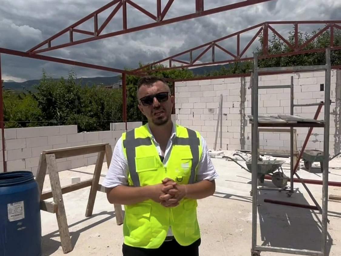 Çelik çatı makasları önünde yelekli şantiye şefi