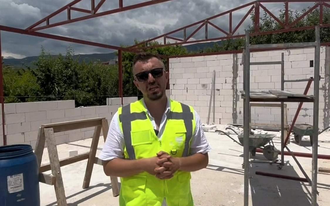 Çelik çatı makasları önünde yelekli şantiye şefi