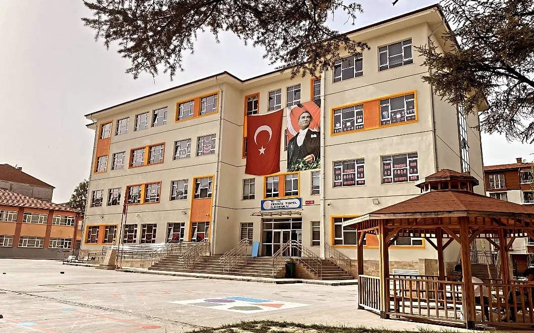 Cengiz Topel İlkokulu cephesi, Türk bayrağı ve Atatürk posteri, önünde ahşap kamelya