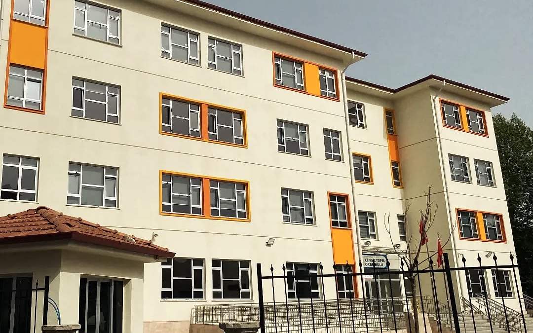 Ortaokul binasının bahçe duvarı ve giriş kapısıyla görünümü