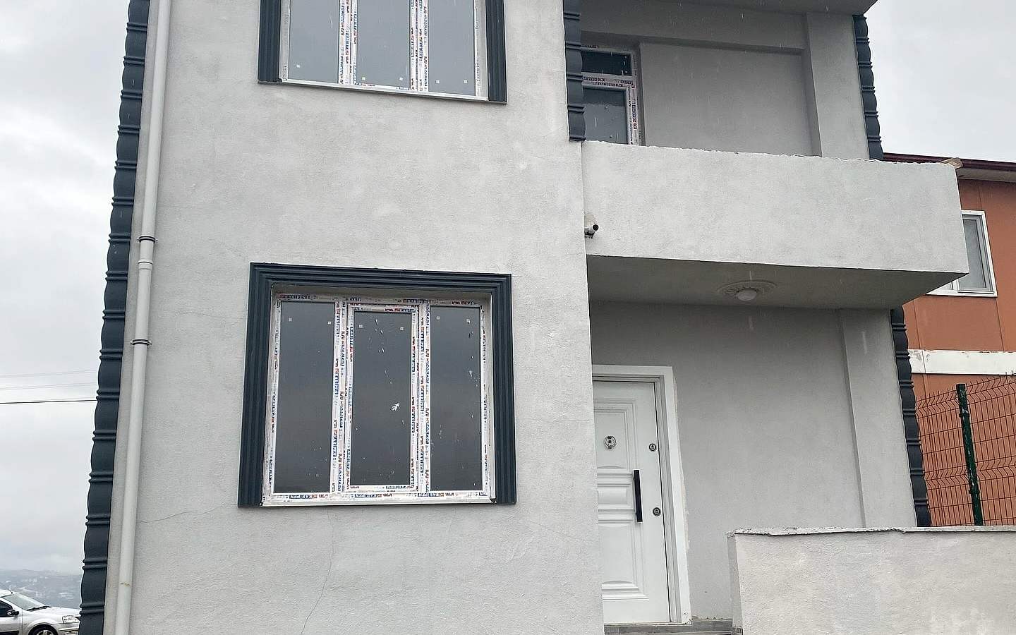 Tamamlanan iki katlı evin açık gri cephesi ve lacivert pencere çerçeveleri