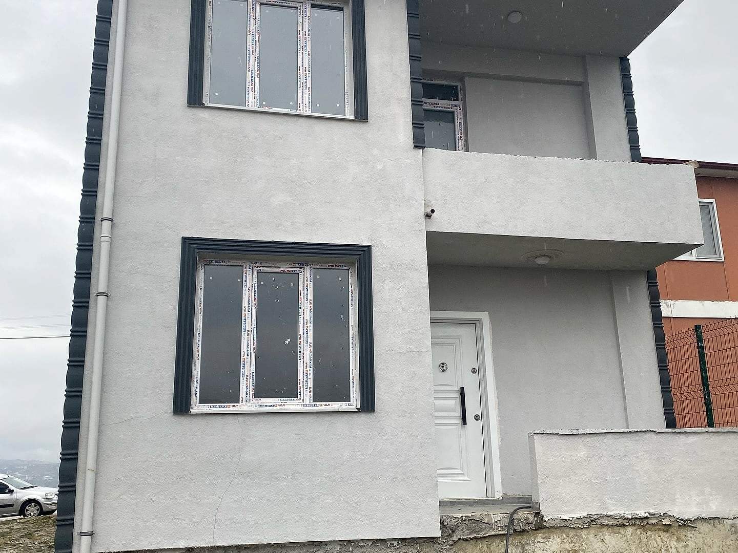 Tamamlanan iki katlı evin açık gri cephesi ve lacivert pencere çerçeveleri