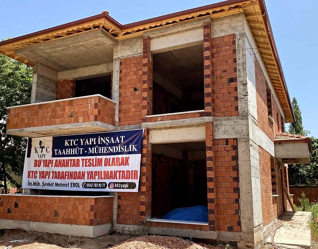 Kaba inşaat aşamasında tuğla duvarlar ve KTC Yapı pankartı