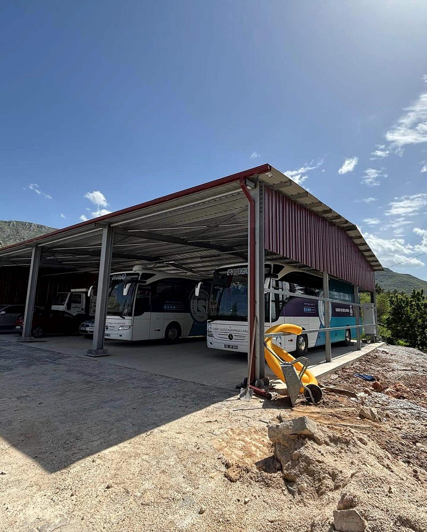 Tamamlanan çelik garajın altında park etmiş üniversite otobüsleri