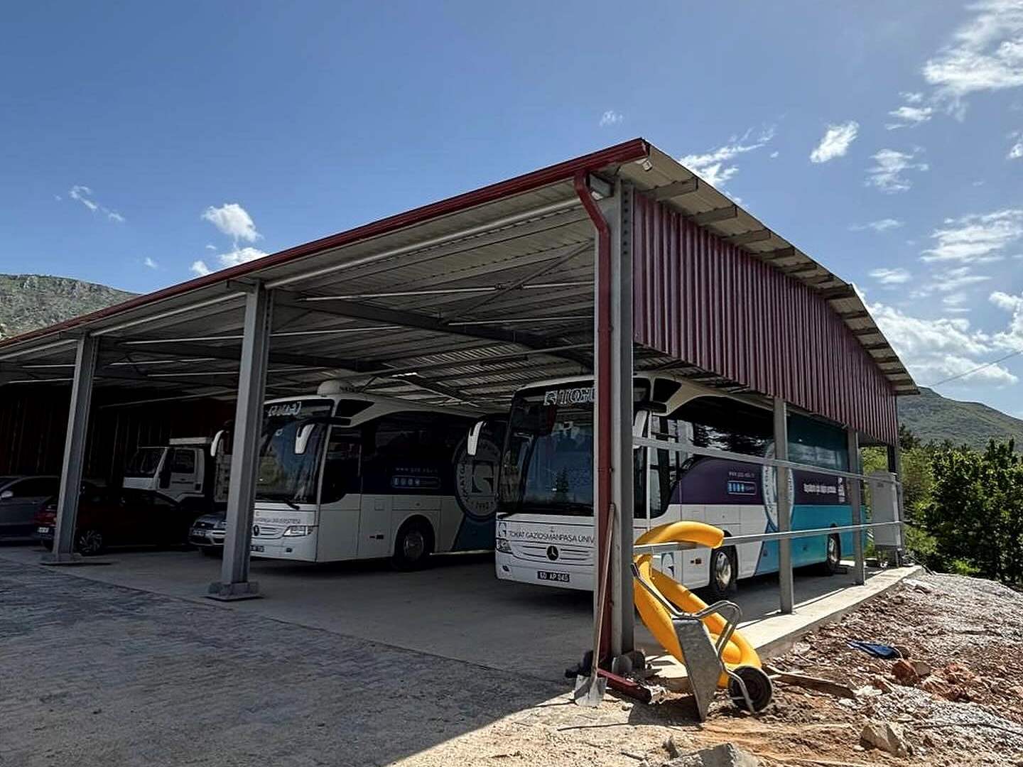 Tamamlanan çelik garajın altında park etmiş üniversite otobüsleri
