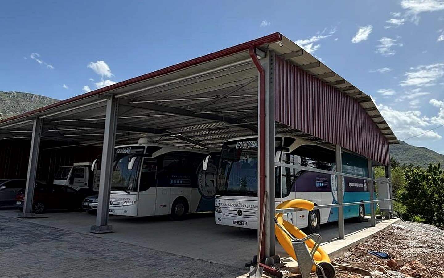 Tamamlanan çelik garajın altında park etmiş üniversite otobüsleri