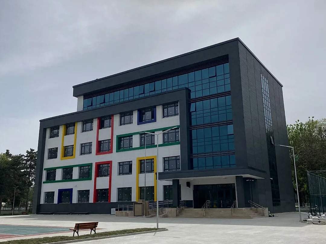 Gri kaplamalı ve renkli pencere çerçeveli okul binası