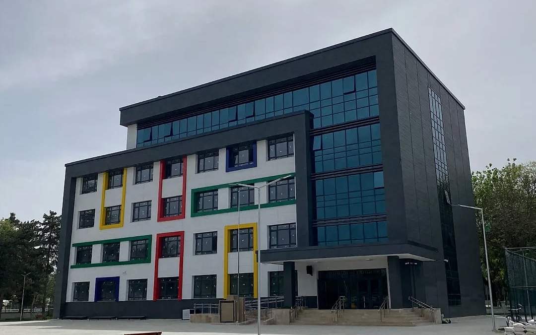 Gri kaplamalı ve renkli pencere çerçeveli okul binası