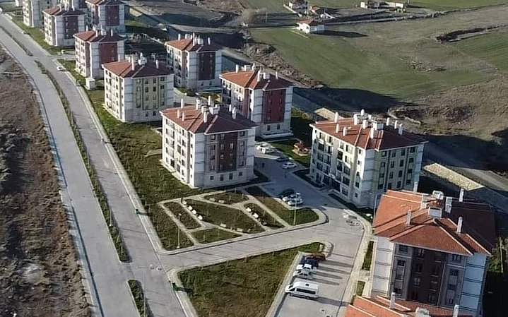 Turhal yerleşkesinin havadan görünümü: vadide yol boyunca sıralanan kiremit çatılı konut blokları