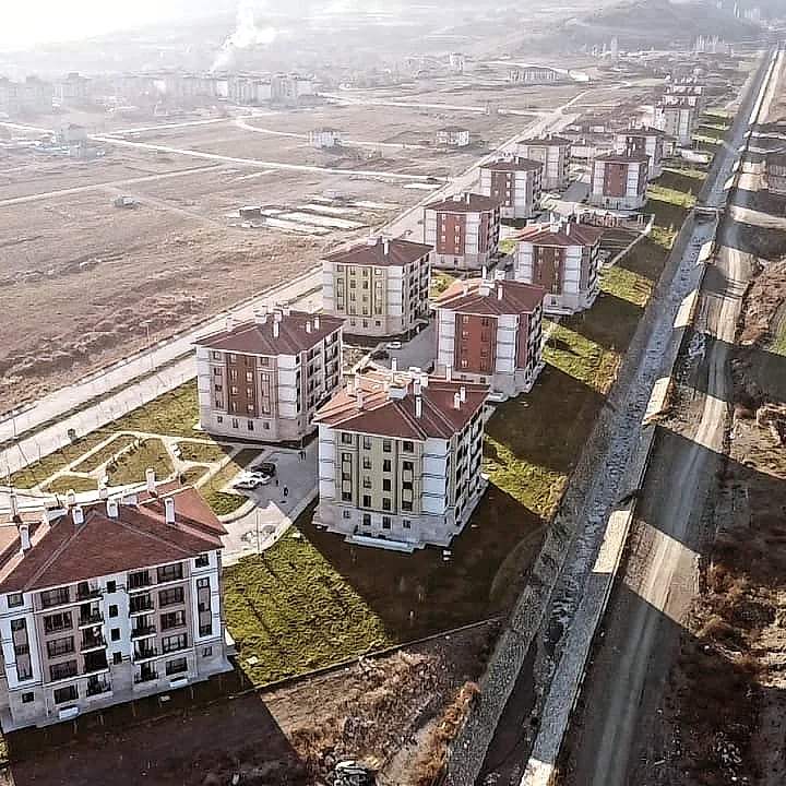 Uzun bir yol boyunca dizilen konut blokları ve arkadaki ova
